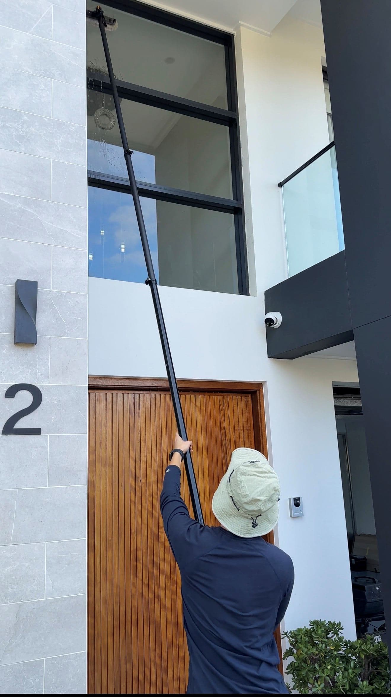 Technician cleaning windows with a water-fed pole at a Sydney home
